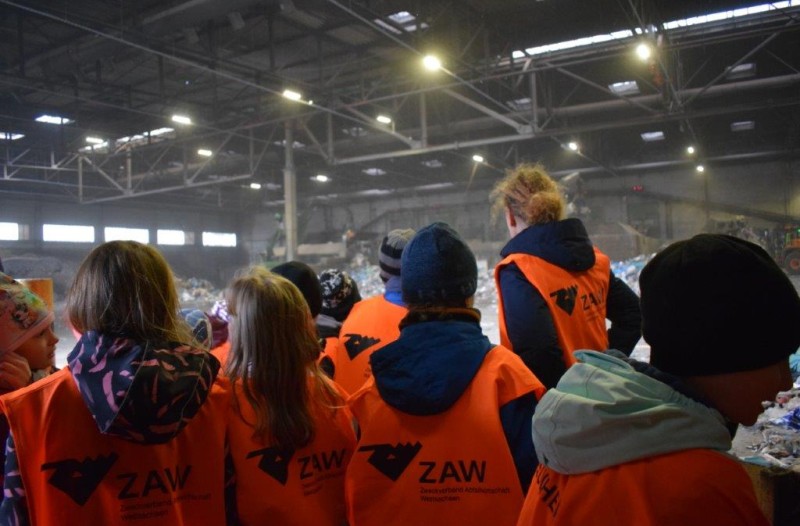 Mehrere Kinder betrachten die Arbeiten in einer Halle der Abfallwirtschaft.